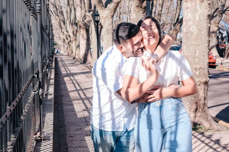 Una pareja se abraza y ríe en una vereda arbolada de Tigre, Buenos Aires
