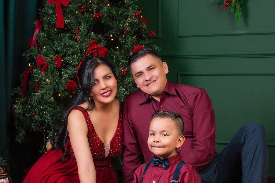 Una familia de tres posa sonriente junto a un árbol de Navidad en Cochabamba, Bolivia