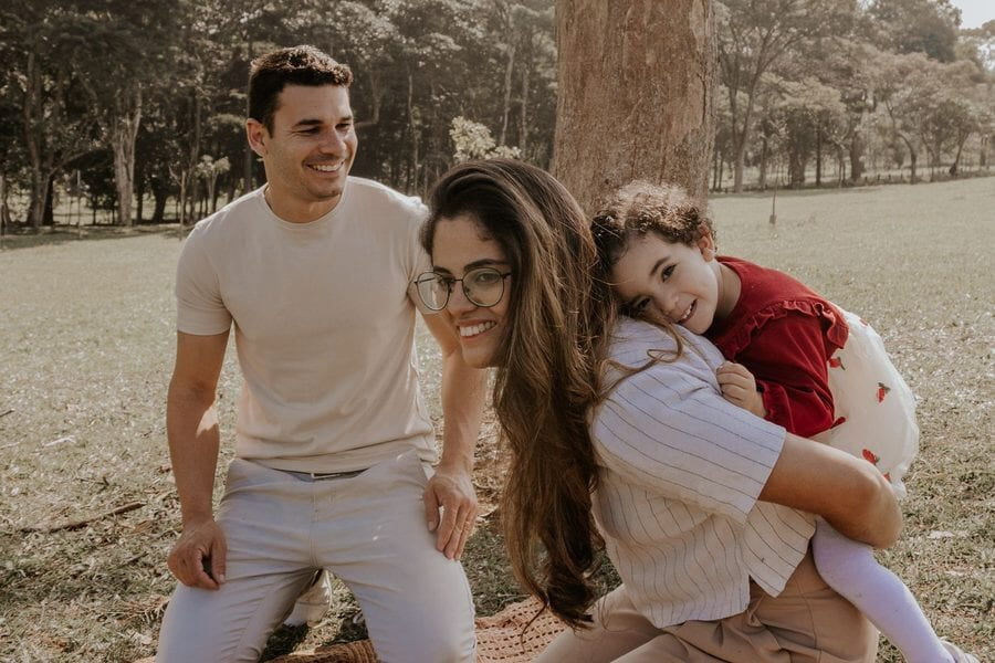Una familia de tres ríe durante un pícnic en un parque de São Paulo